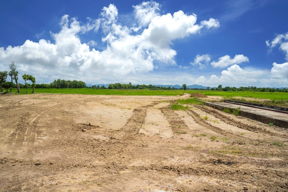 Zone de récupération vide, sol compact vacant du chantier de construction avec pneus de voiture imprimé et belle vue sur le paysage et le ciel bleu