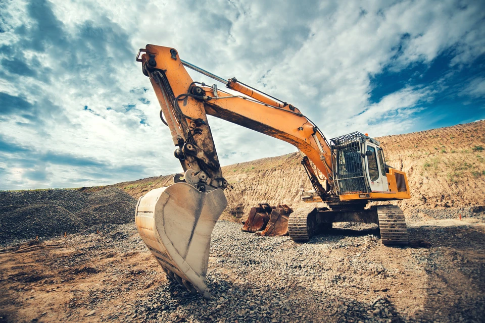 Chantier de terrassement en plein air avec pelleteuse hydraulique orange en opération d'excavation