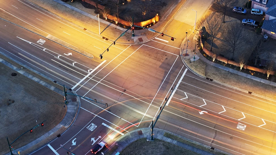 Réunion de chantier en intérieur avec trois professionnels du bâtiment portant des casques de sécurité colorés, consultant des plans architecturaux
