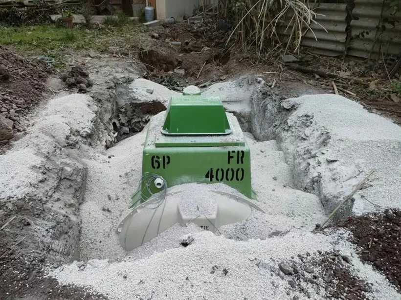 Scène extérieure sur pelouse verte avec dispositif sanitaire blanc posé sur pierre plate