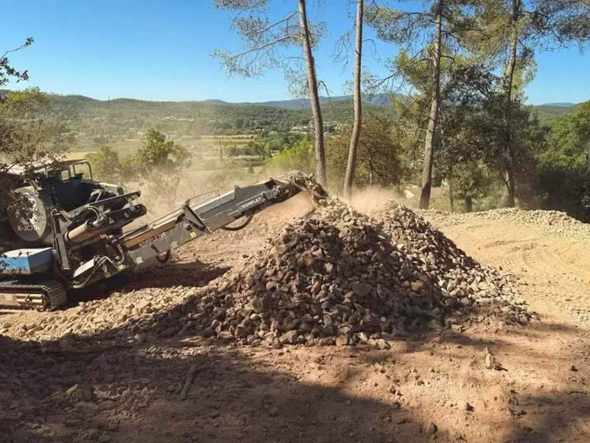 Un grande rouleau de tissu paysager repose sur un chantier marqué par la terre et le gravier