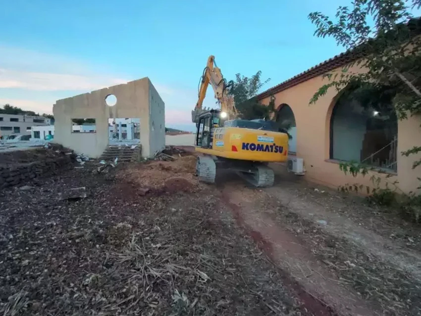 Terrain résidentiel vacant avec pelouse clairsemée et zones de terre nue, entouré de clôtures en bois