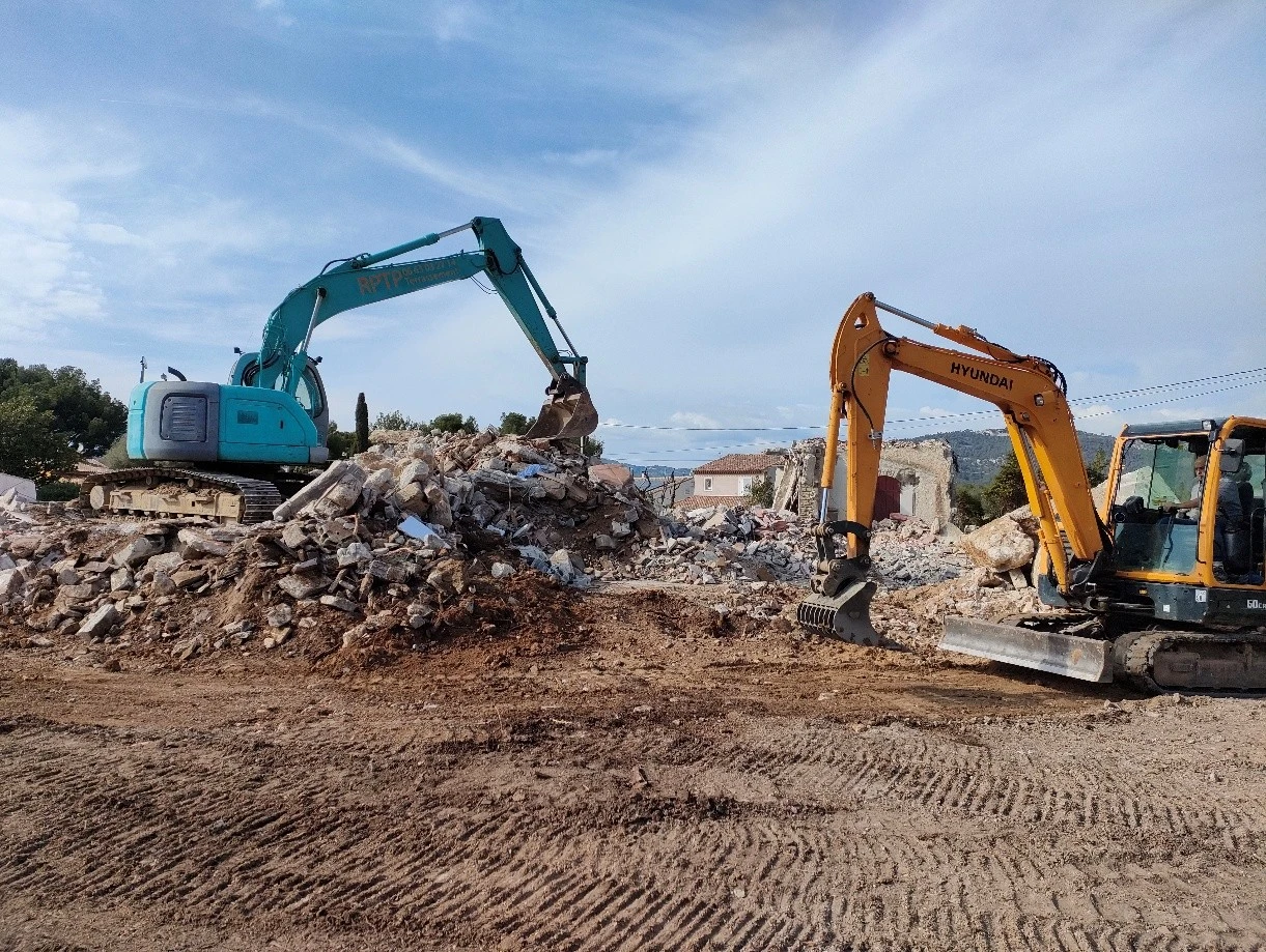 Chantier de terrassement en extérieur avec pelleteuse hydraulique orange sur chenilles en action